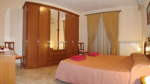 A bedroom with a large bed, a wardrobe, a mirror, a table, and curtains. - B&B Esperanca (Frascineto)