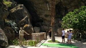 A stone pathway leading to a cave entrance, surrounded by a metal railing and greenery. - B&B Esperanca (Frascineto)