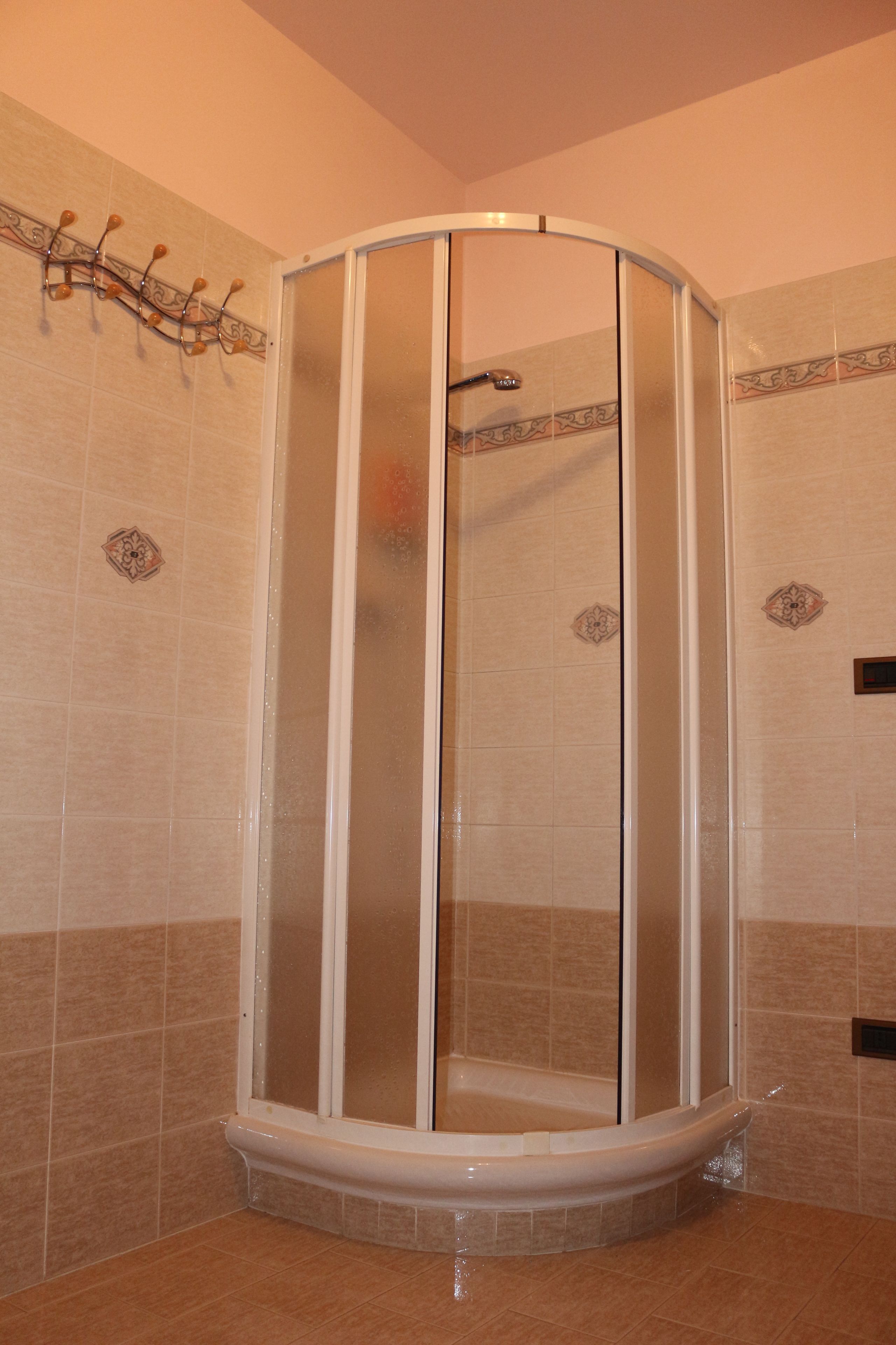 A corner shower enclosure with a glass door and a showerhead.