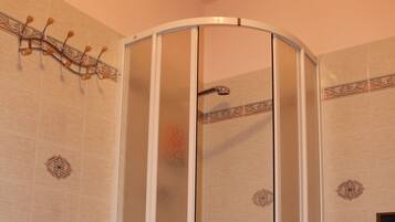 A corner shower enclosure with a glass door and a showerhead.