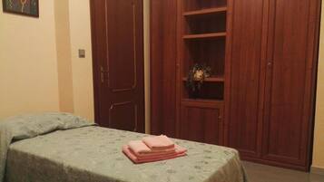 Un dormitorio con cama, un armario de madera y una estantería con una planta.