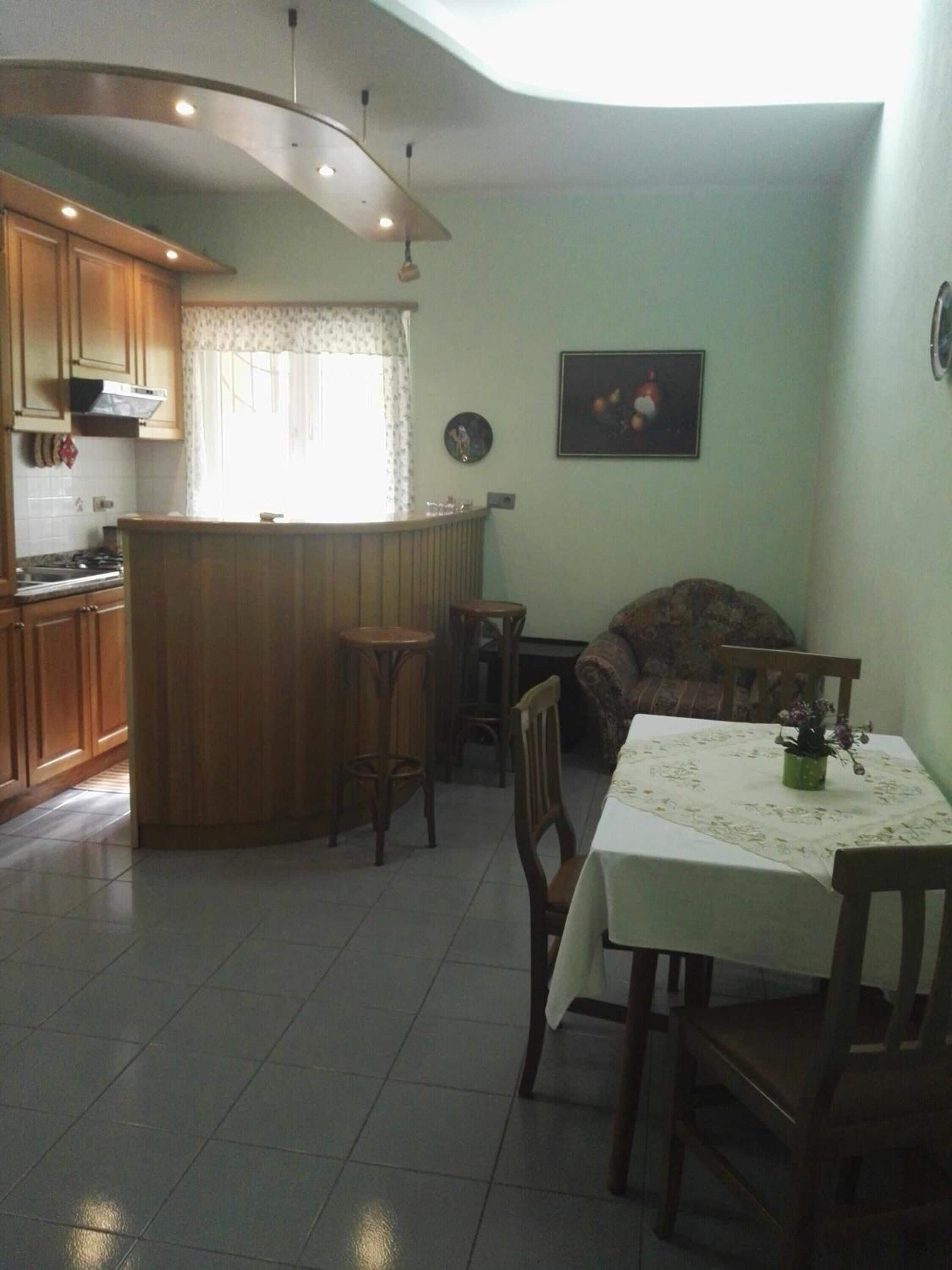 A kitchen with wooden cabinets, a central island, and a dining area with a table and chairs.