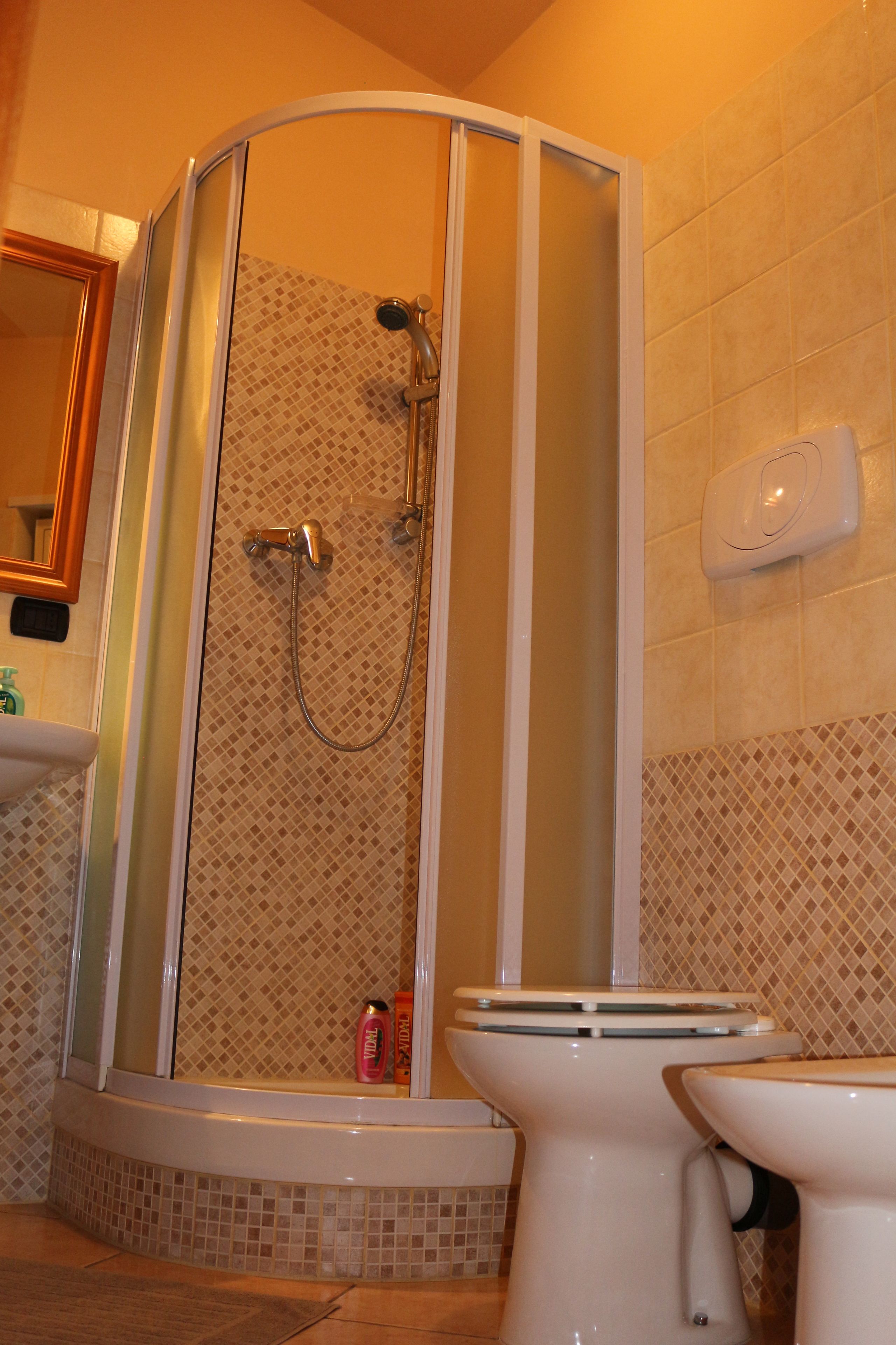 A bathroom with a glass-enclosed shower, a toilet, and a sink.