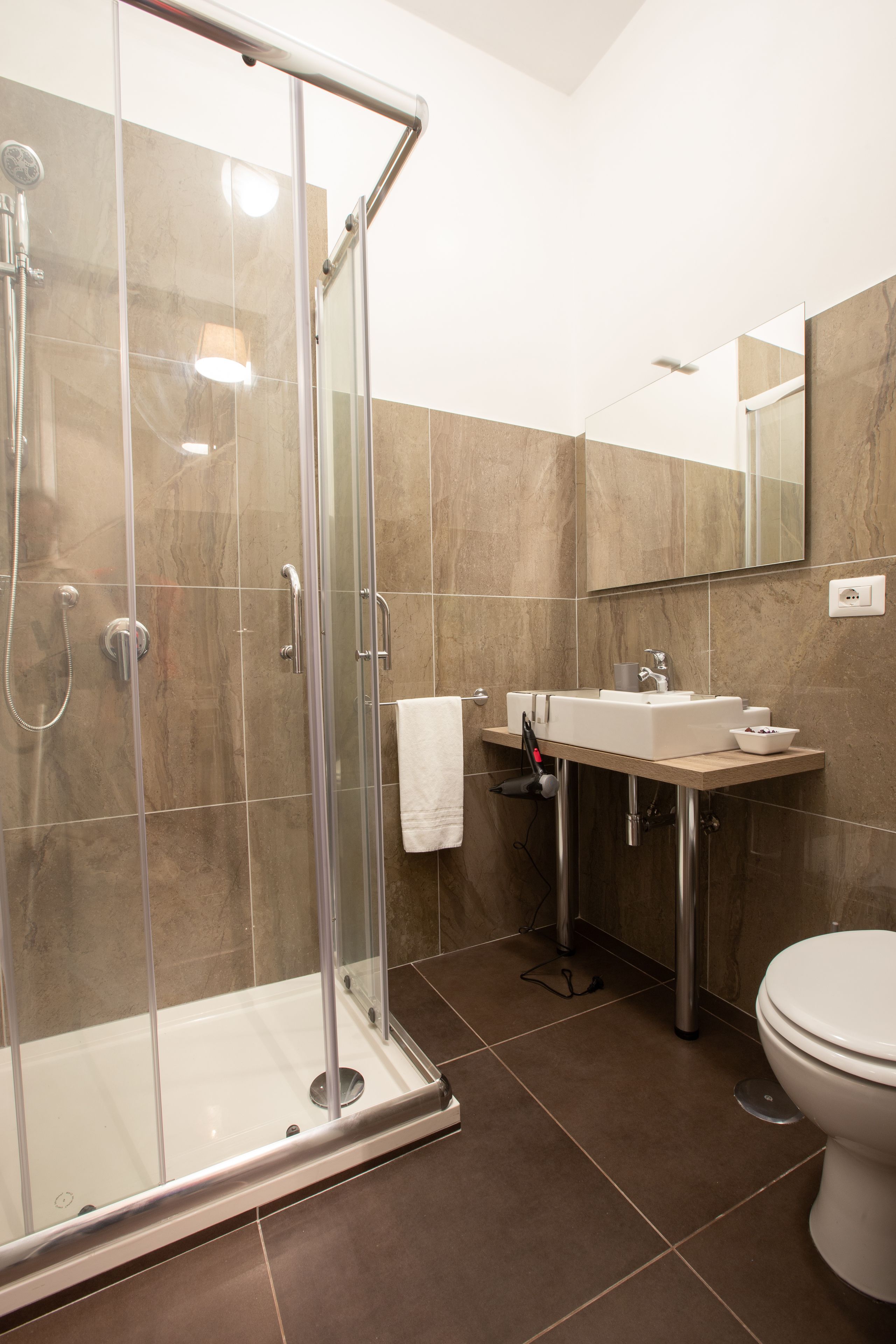 A modern bathroom with a glass-enclosed shower, a sink, and a toilet.