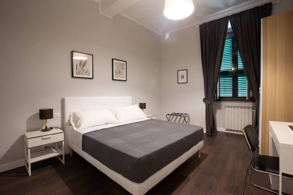 Un dormitorio moderno con cama, mesitas de noche, un escritorio y una silla.