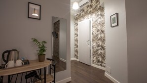 Uma cozinha moderna com uma mesa de madeira, cadeiras, chaleira, xícaras e um vaso com planta.