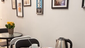 Um café com uma pequena mesa redonda, cadeiras, uma cafeteira, chávenas e um croissant.