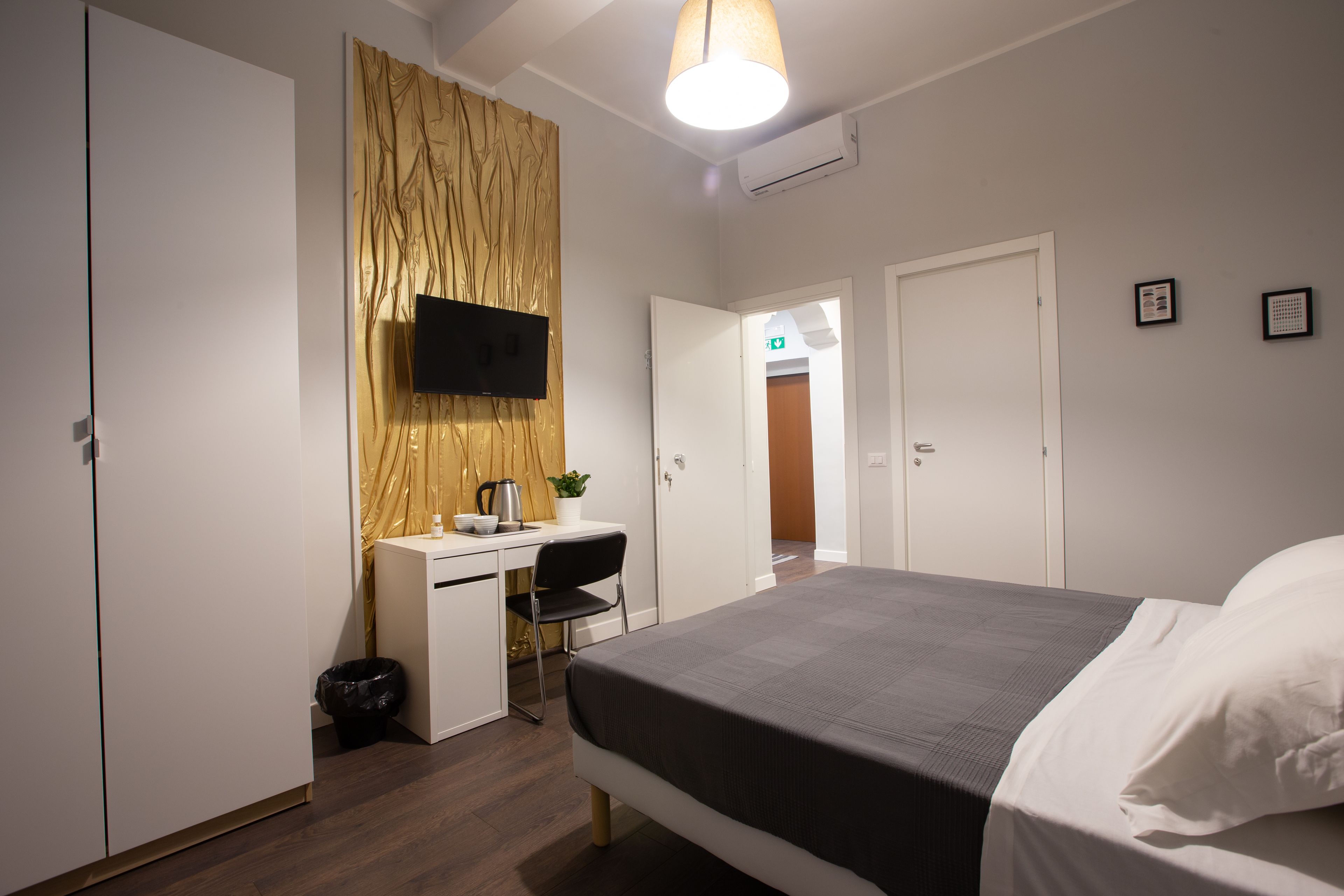A bedroom with a bed, a desk, a chair, a TV, and a wardrobe.