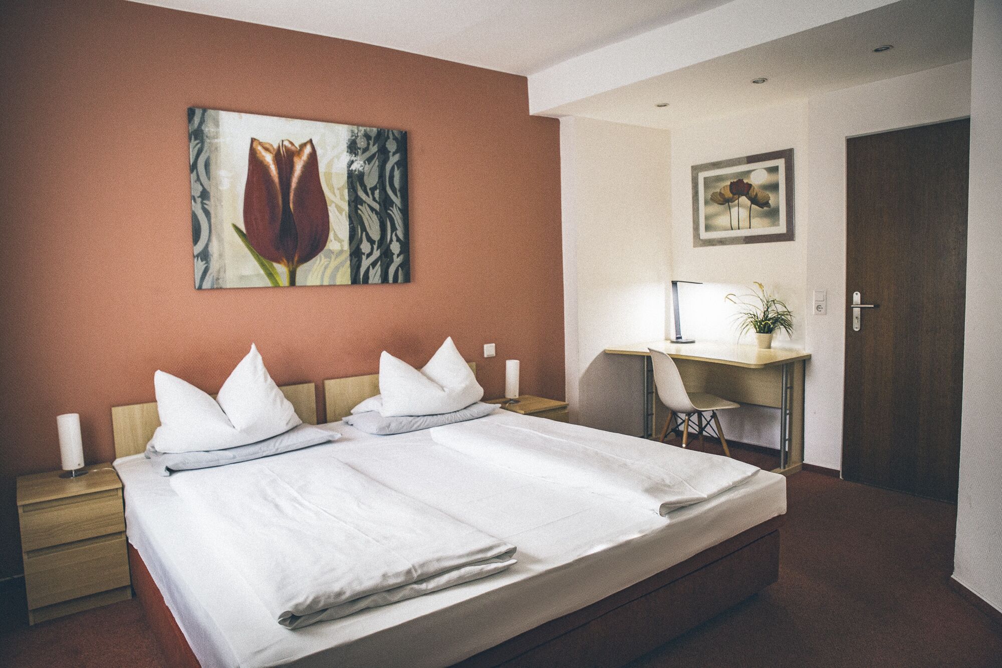 Habitación de hotel con una cama grande, un escritorio, una silla y una puerta.