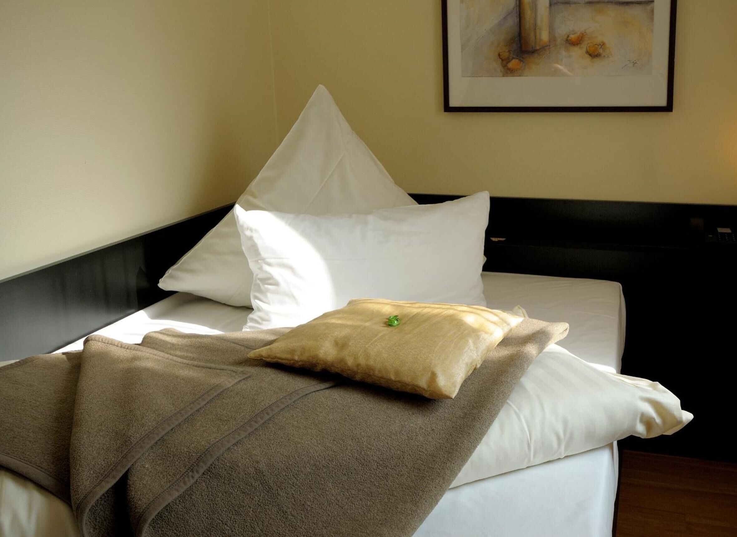 Una cama bien hecha con sábanas blancas y un edredón color beige.