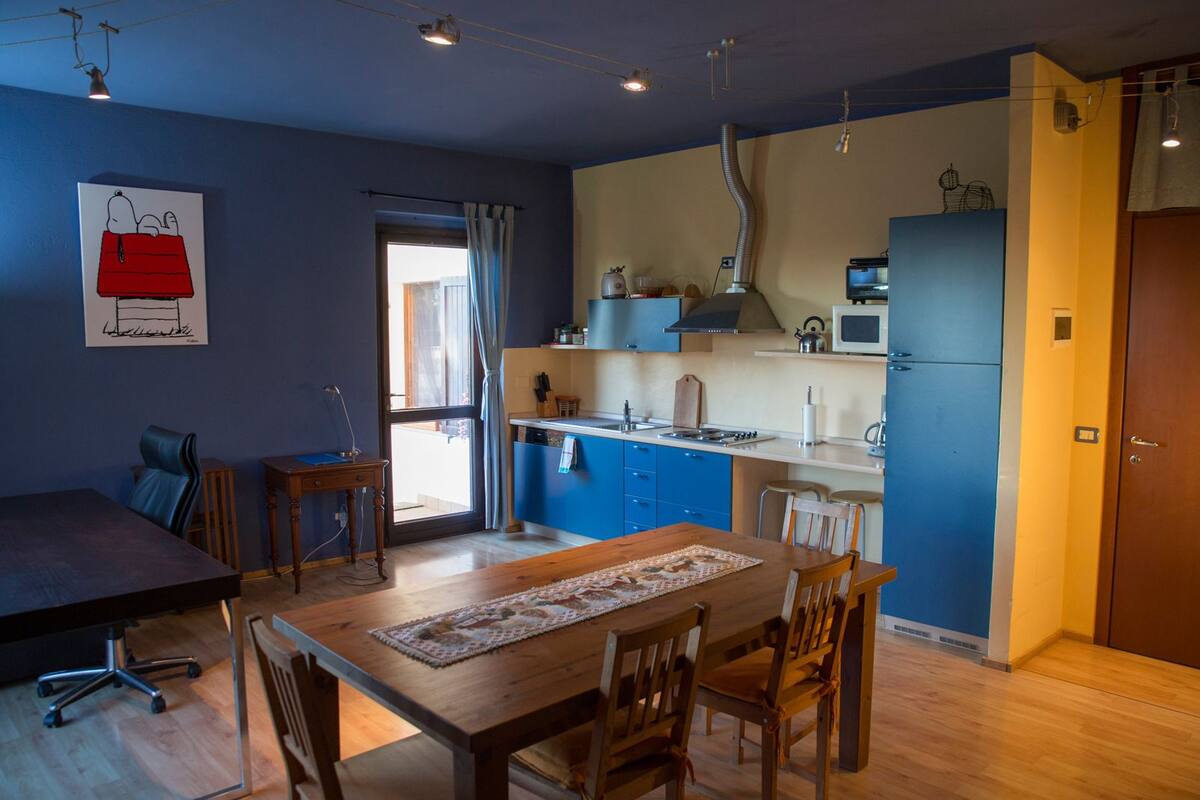 Una cocina moderna con armarios azules, una mesa de comedor de madera y un ventanal grande.