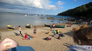 A beach with boats, people, and a rocky shoreline.