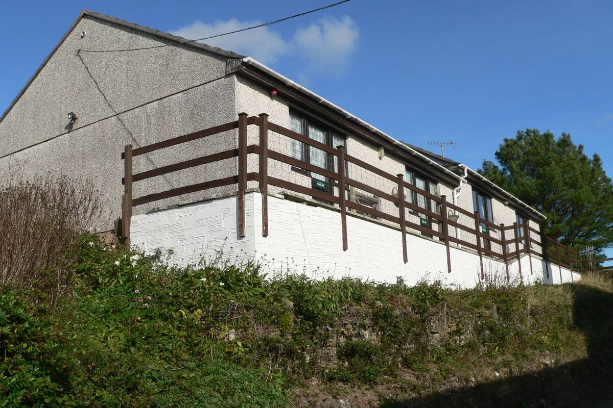 A white building with a brown wooden fence, surrounded by greenery.