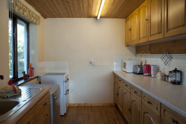 A compact kitchen with wooden cabinets, a microwave, a toaster, and a kettle.