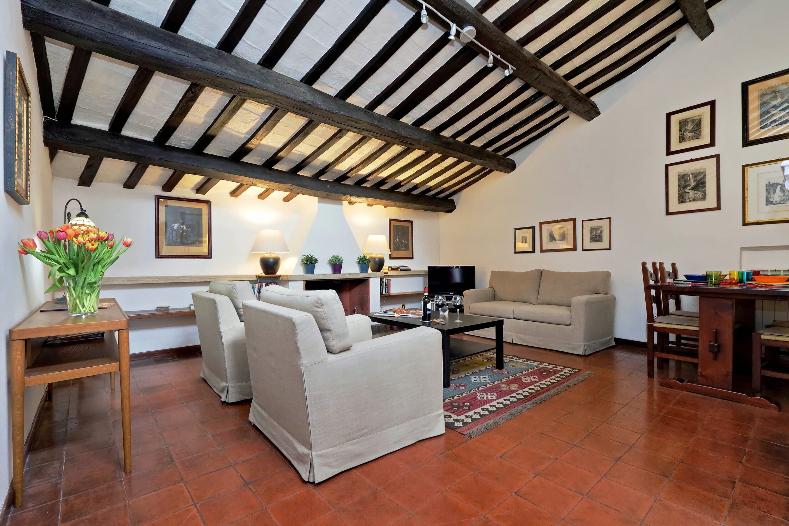 A living room with a high ceiling, exposed beams, a sofa, a coffee table, and a TV.