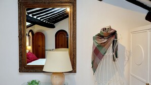 Un espejo con un marco decorativo, una mesa con una lámpara y una puerta con timbre blanco.