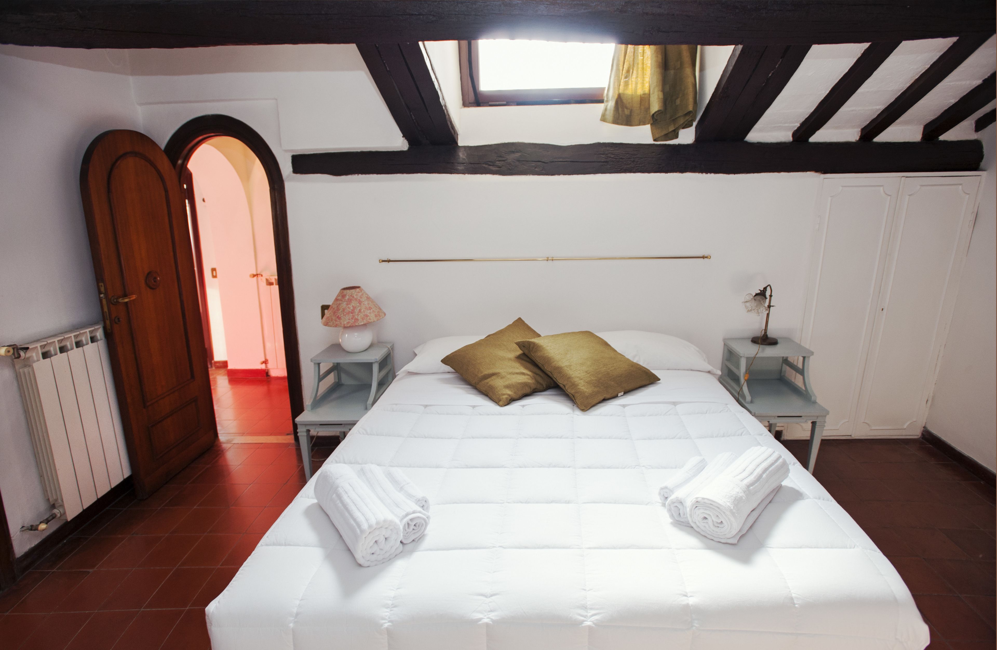 Una camera da letto con un letto, due comodini, una finestra e una porta.