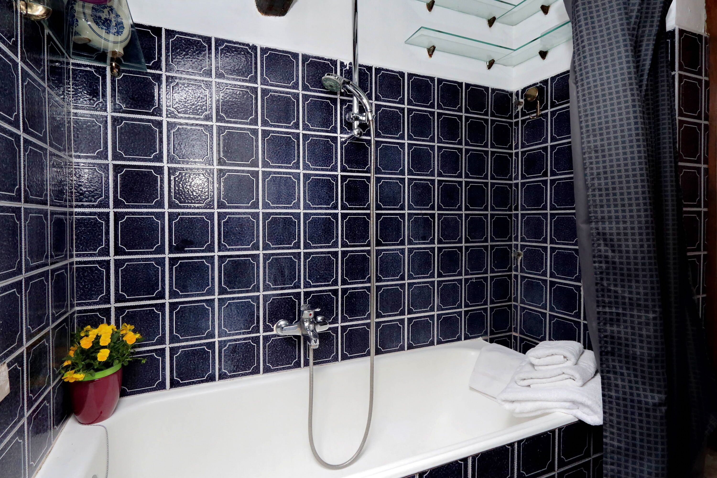 A bathroom with a white bathtub, a shower, and a tiled wall.