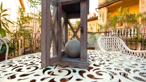 Un farol de madera con un objeto esférico en su interior, sobre una mesa de metal blanco perforado.
