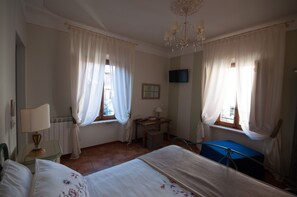 Ein Hotelzimmer mit Bett, Schreibtisch, Stuhl, Fernseher und einer Kristallleuchter.