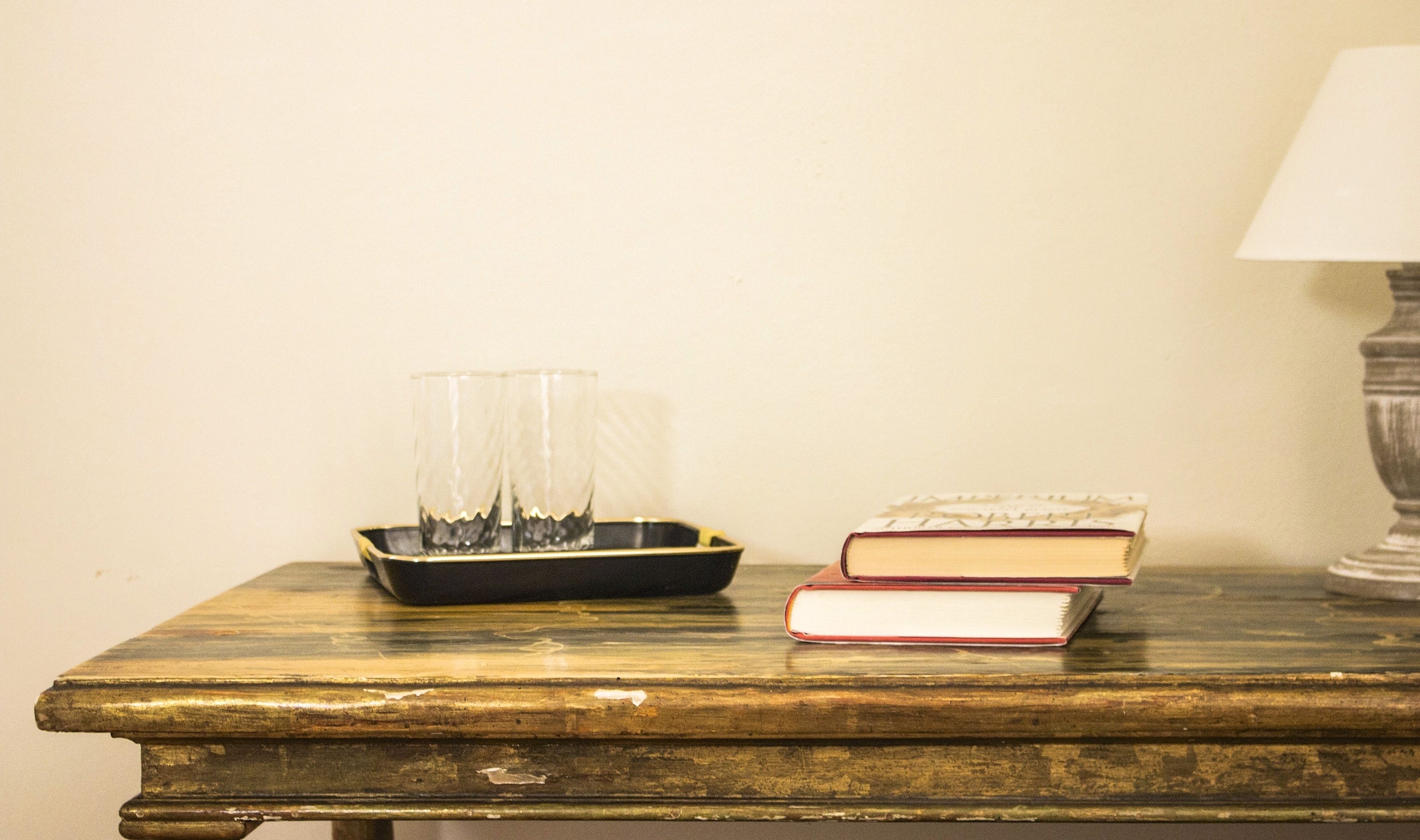 Una mesa de madera con dos libros y una bandeja de vasos.