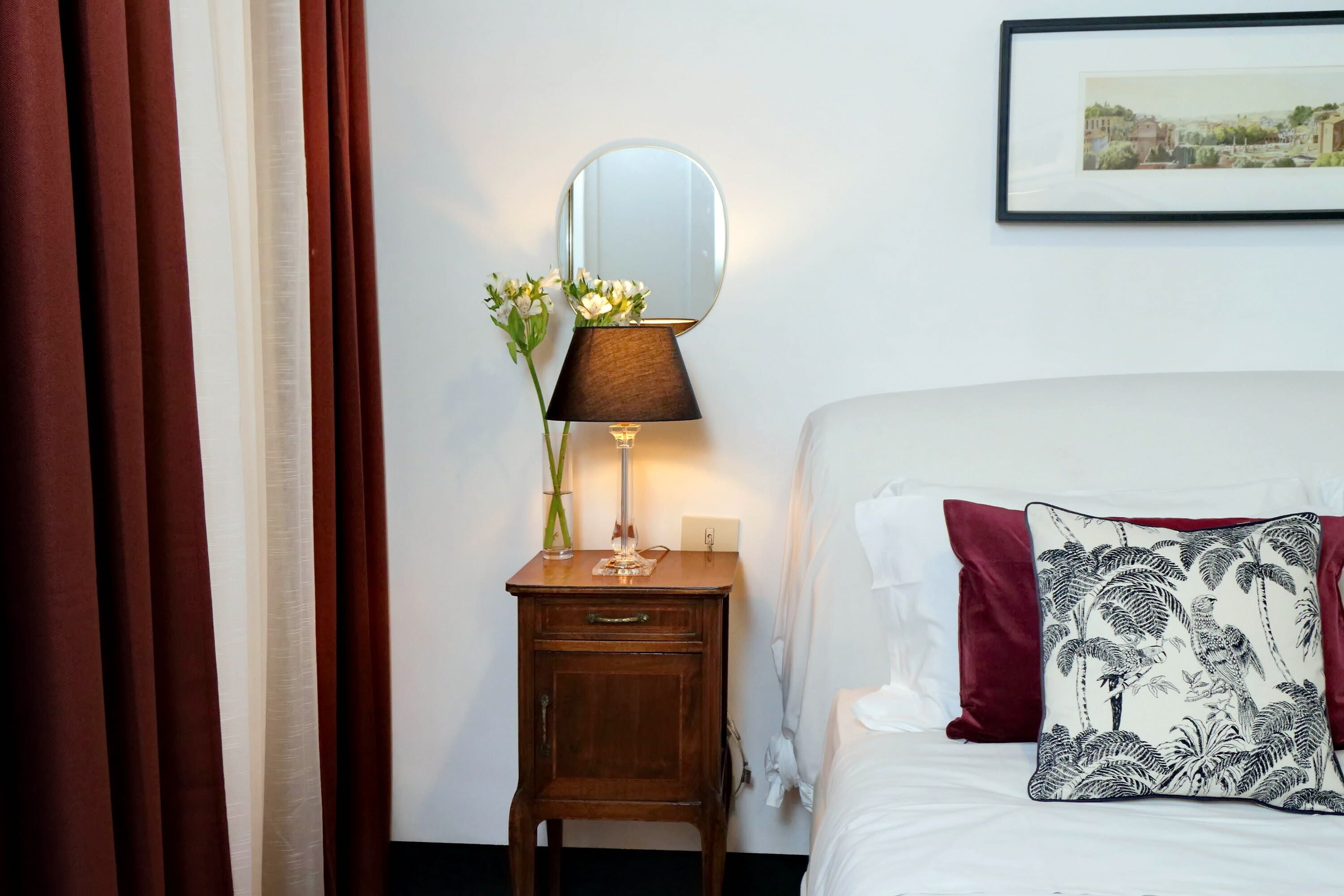 A neatly made bed with a white pillow and a decorative pillow with a tropical print.