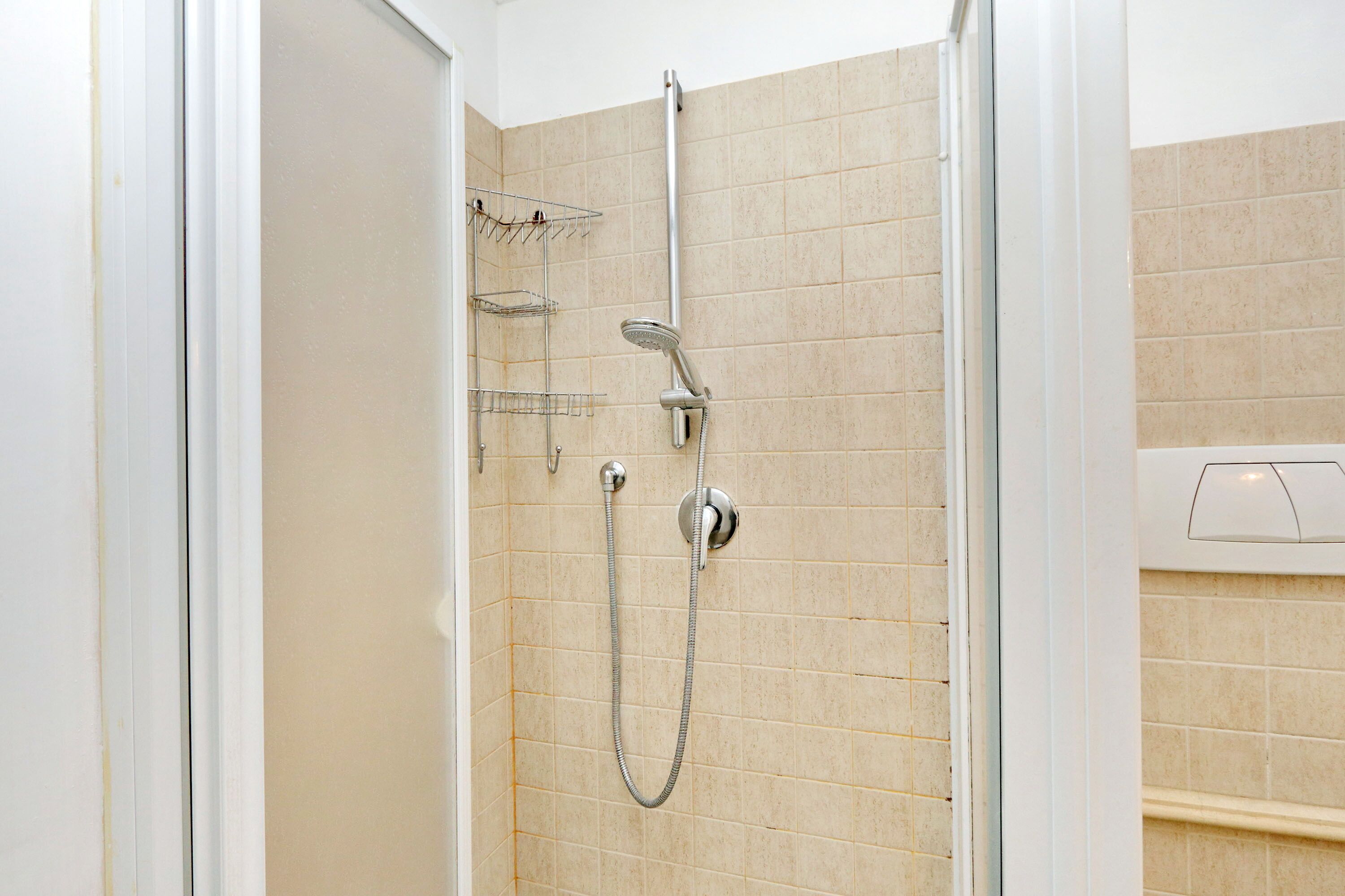 A shower with a handheld showerhead and a wall-mounted faucet.