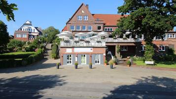Traditional European-style hotel with a gabled roof and symmetrical facade, set amidst a charming garden.