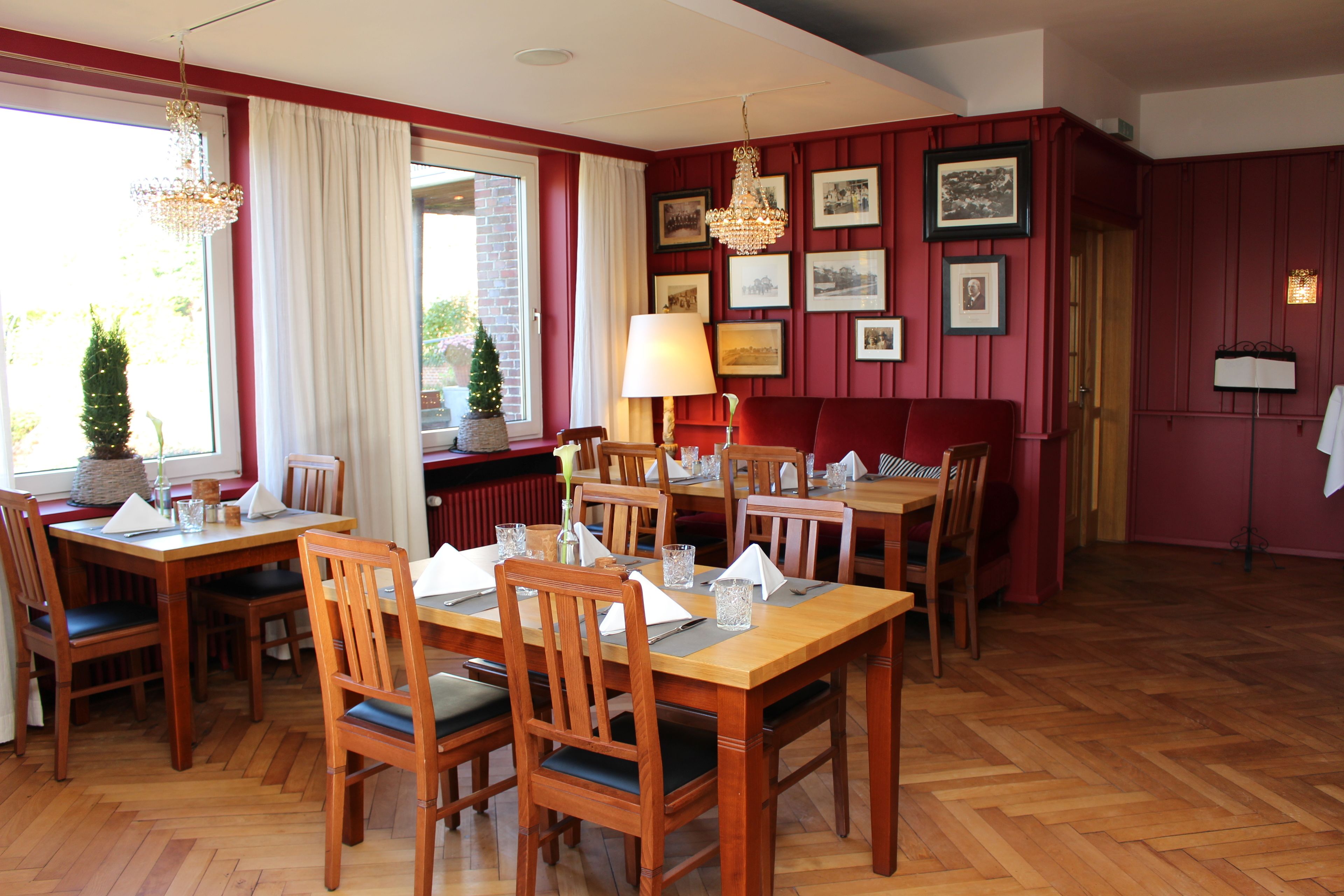 A dining area with wooden tables and chairs, a chandelier, and framed pictures on the walls.