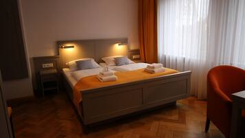 A hotel room with a large bed, two bedside tables, a chair, and a window with curtains.