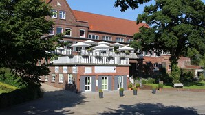 A hotel with a brick facade, multiple windows, and outdoor umbrellas. - Hotel Zur Treene (Schwabstedt)