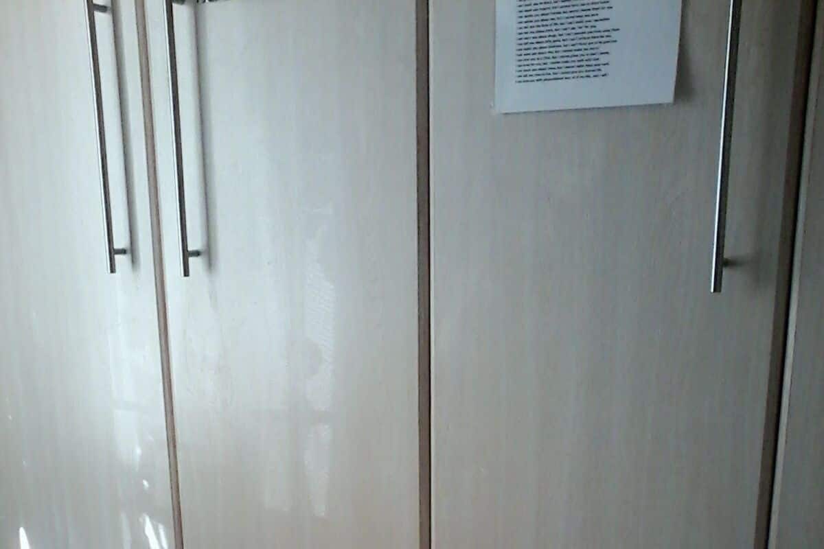 Una habitación con un armario grande, suelo de baldosas y un papel en la pared.