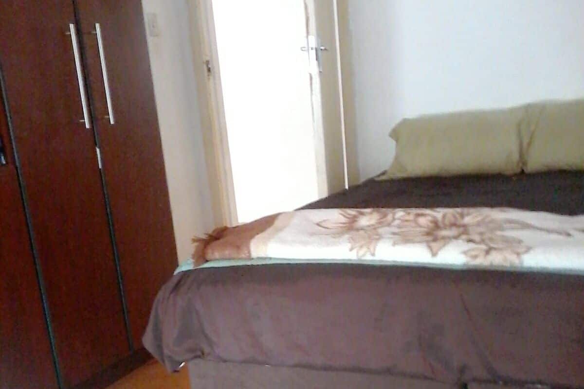 Un dormitorio con cama, armario de madera y alfombra azul estampada.
