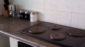 Una cocina con estufa, armarios y un esparcidor de especias.