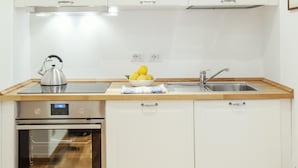 A kitchen with white cabinets, a stainless steel kettle, a sink, and a dishwasher. - Bufalo - WR Apartments (Rome)
