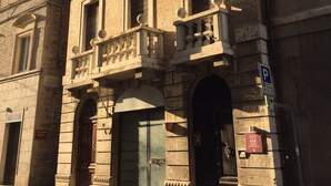 A historic building with a central entrance, arched doorways, and a balcony with balustrades. - B&B Porta Santa Lucia (Fermo)