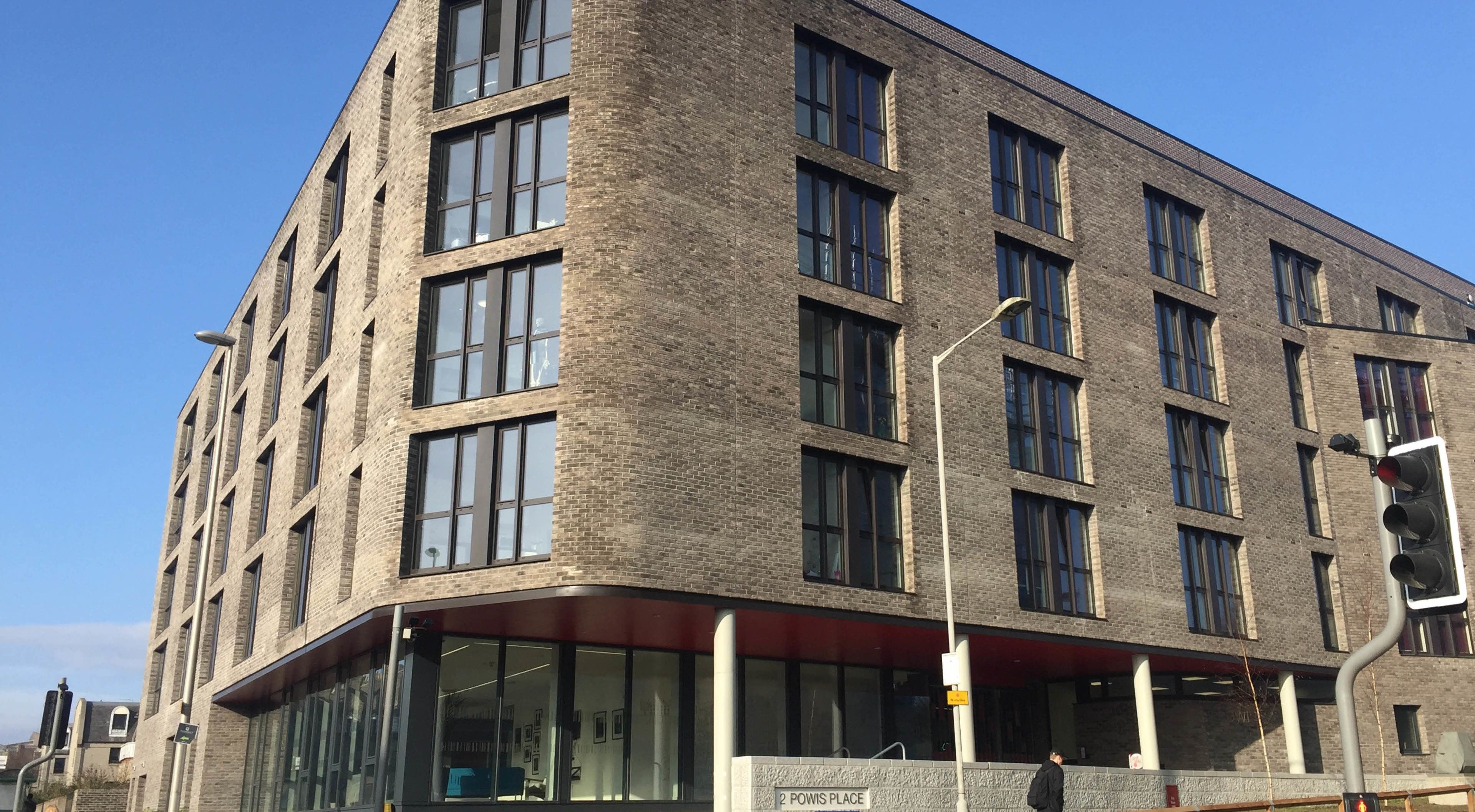 A multi-story building with a brick facade, large windows, and a ground-level entrance.