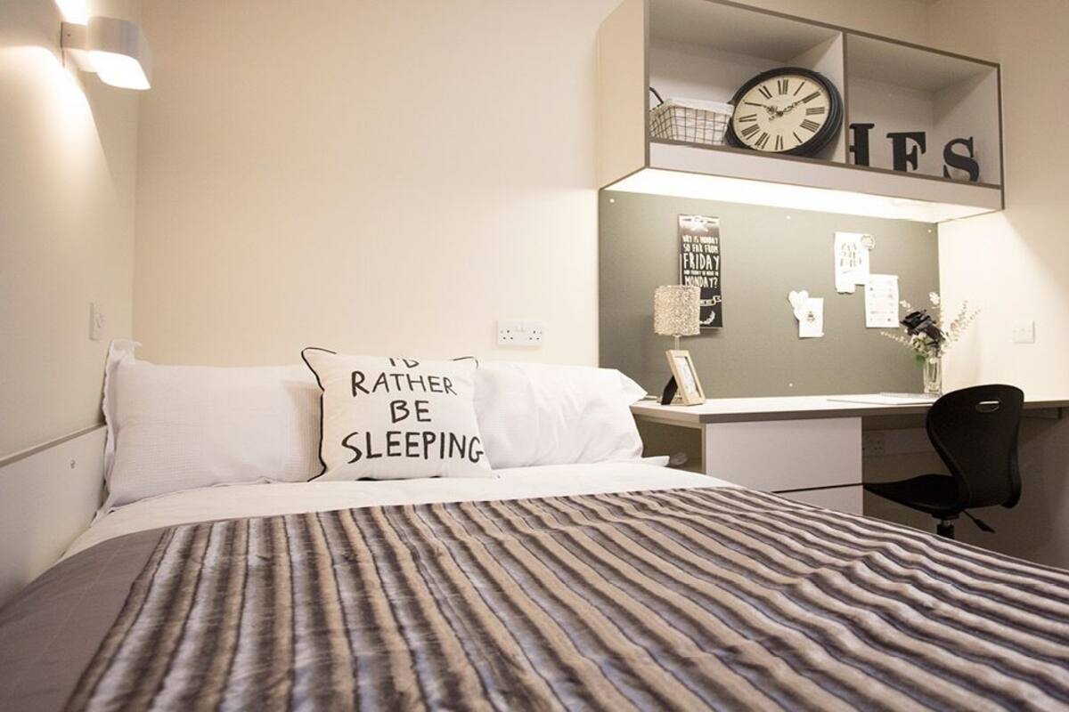 A bedroom with a bed, a desk, and a chair.