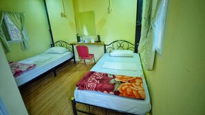 A small room with two single beds, a desk, and a chair.