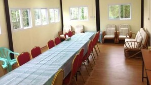 A conference room with a long table, red and white chairs, and large windows.