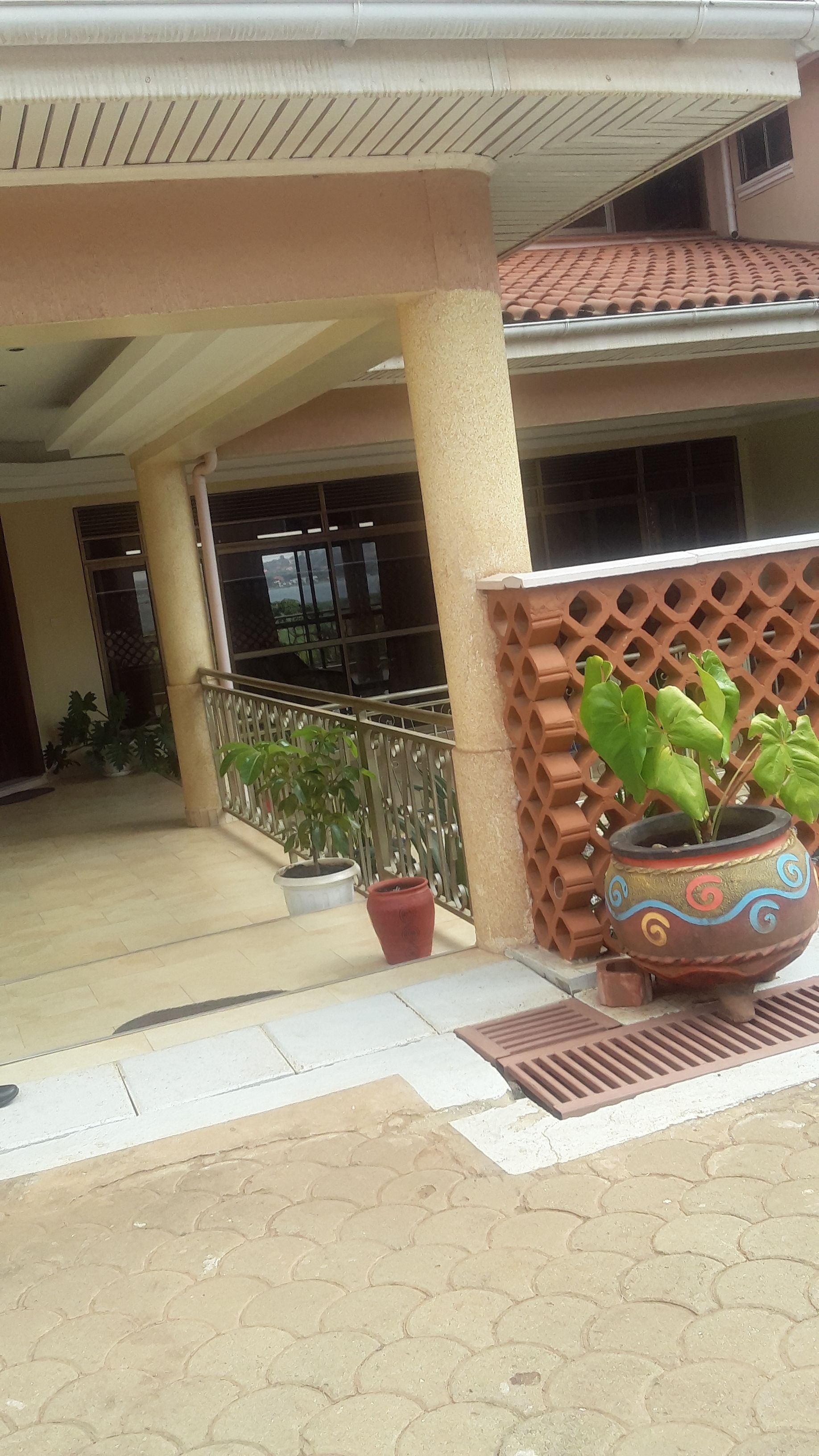 Entrada de un edificio con un vestíbulo cubierto, plantas en macetas y una maceta decorativa.