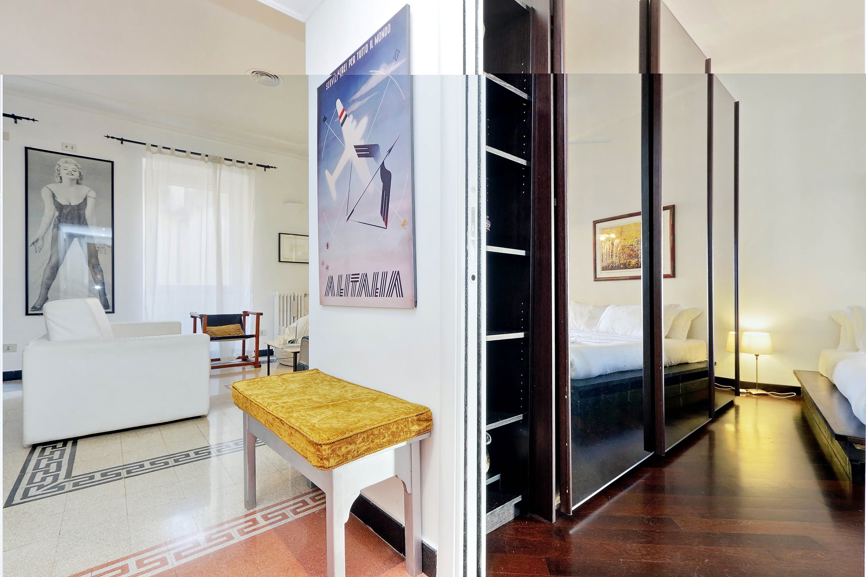 A hotel room with a bed, a desk, a chair, a sofa, and a poster on the wall.