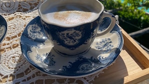A cup of coffee on a tray with a scenic view of a mountainous landscape and a body of water.