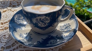 A cup of coffee on a tray with a scenic view of a valley and mountains in the background.