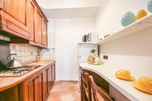 Une cuisine avec des meubles de rangement en bois, une cuisinière à gaz, un évier et un plan de travail blanc.
