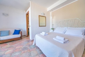 Une chambre à coucher comprenant un lit, un canapé, un miroir et une porte donnant sur une autre pièce.