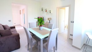 A modern living room with a sofa, dining table, and chairs. There is a potted plant on the table. - Casa Ninà (Sant'Agnello)