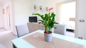 A modern hotel room with a dining table, a potted plant, a television, and a bed. - Casa Ninà (Sant'Agnello)