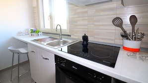 A modern kitchen with a built-in dishwasher, a stove, and a sink. - Casa Ninà (Sant'Agnello)