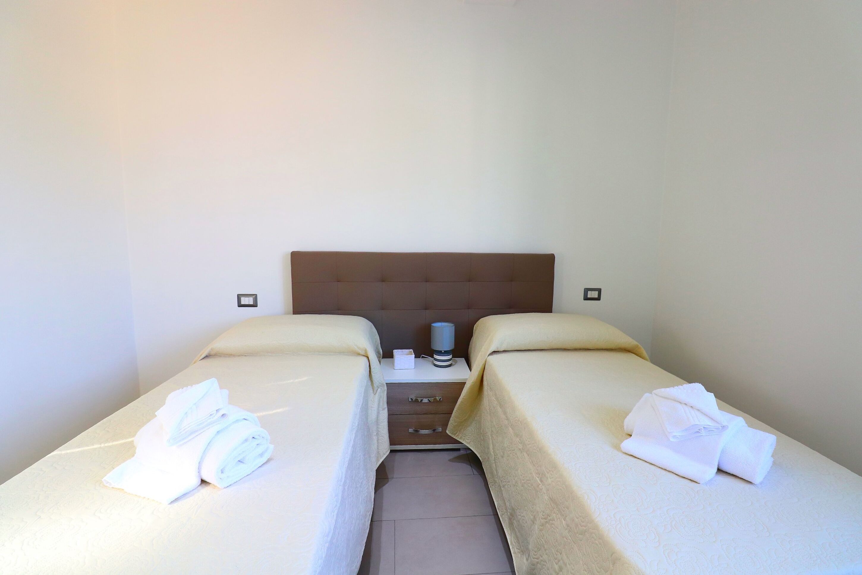 A twin room with two beds, a nightstand, and a coffee maker.